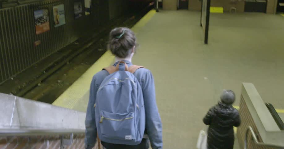 Two people walk down stairs to a subway platform