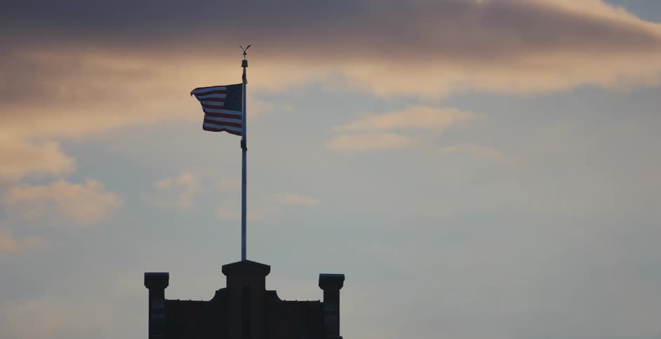 Wind blowing through an American flag on top of a building