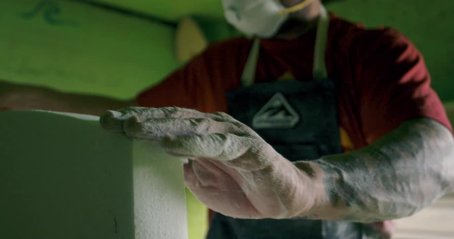 A man with a mask and apron using a tool to shape stone