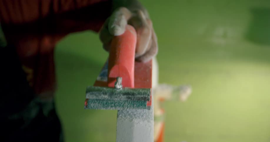 A person using a hand held sander on a piece of wood