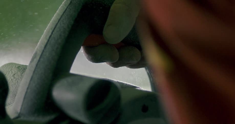 A person holding a machine sanding on a material that is smoking
