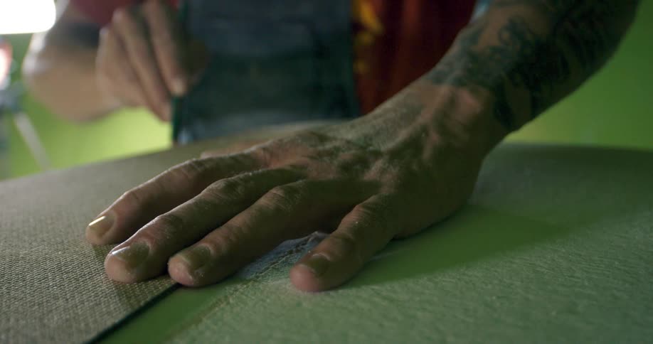 A man inside holds fabric down as he traces around it