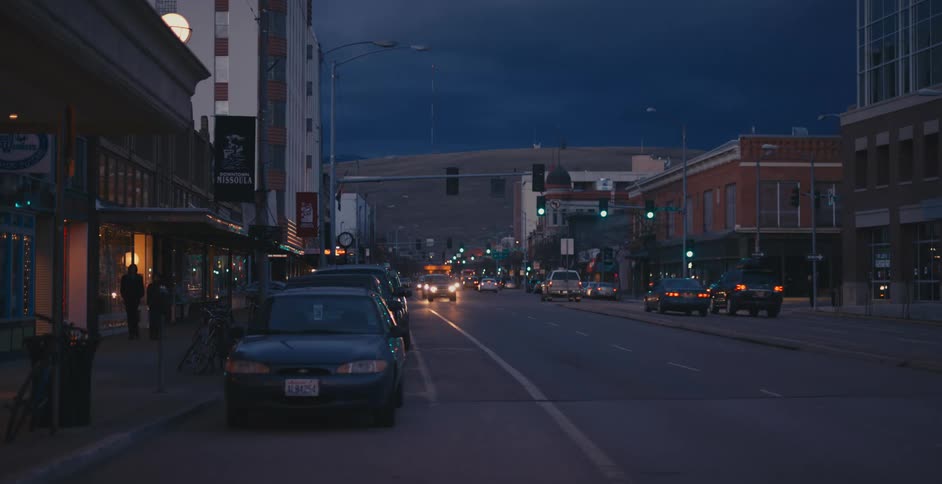 Traffic traveling and parked along a wide street in a metropolis at night