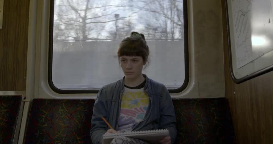 A woman sketches on a train