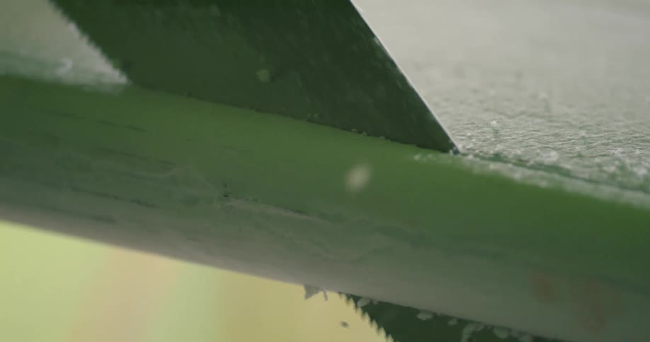 A metal saw cutting the styrofoam of a surfboard on a workshop
