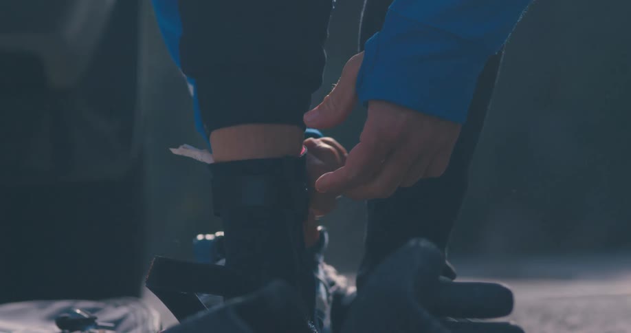 Person wearing long sleeves with thumb slots unfastens strap from ankle