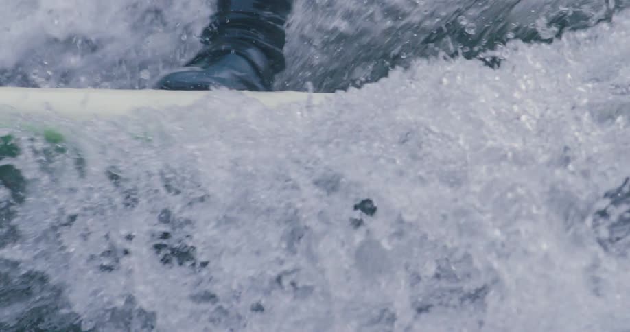 A surfer rides a wave with a multicolor surfboard