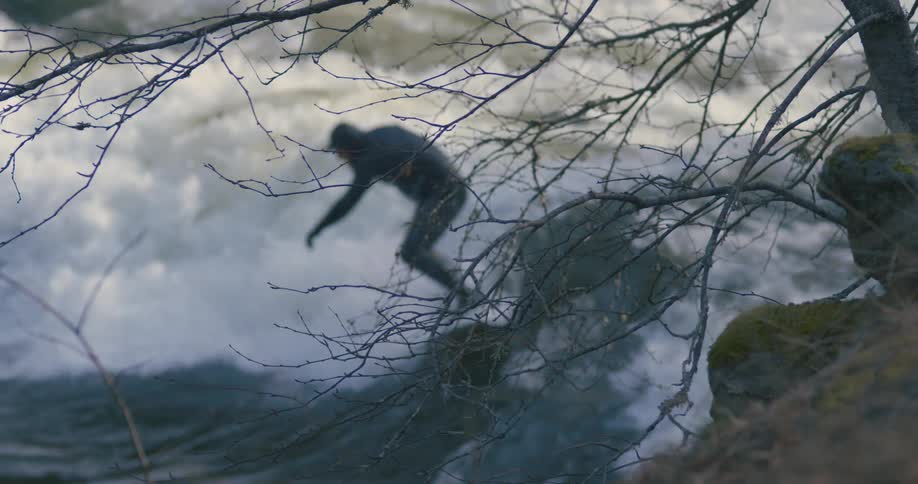 A surfer rides a wave on the ocean near a cliff