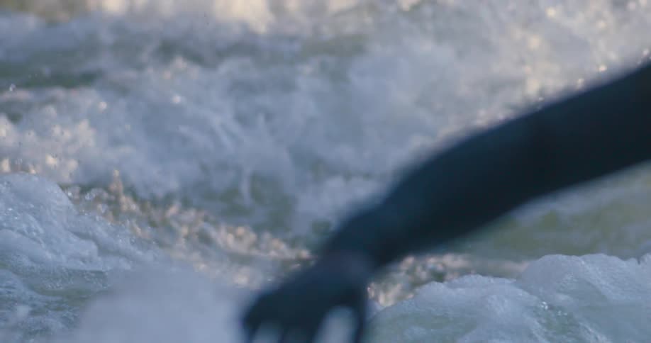 Man wearing cap and suit stretches out arm near churning white water