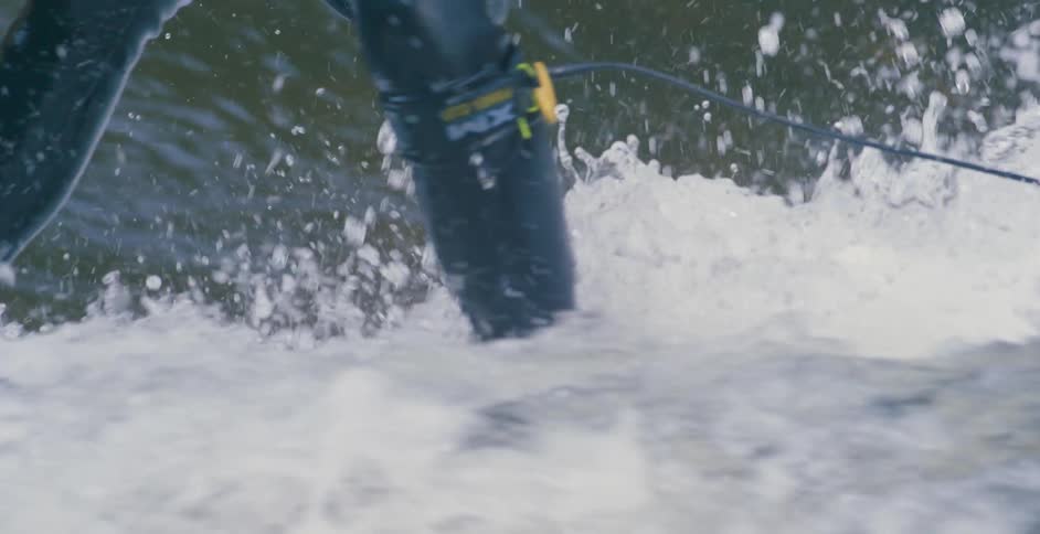 A surfer in a full coverage black wetsuit rides a strong ocean wave