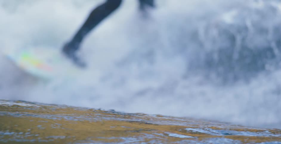 Ocean waves surround a surfer in a wetsuit on a surfboard