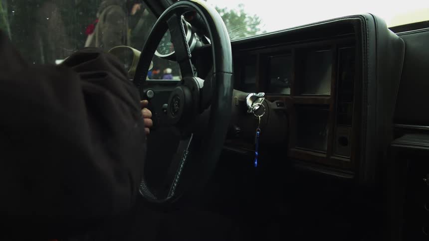 A person in a safety vest starts and begins to drive a vehicle