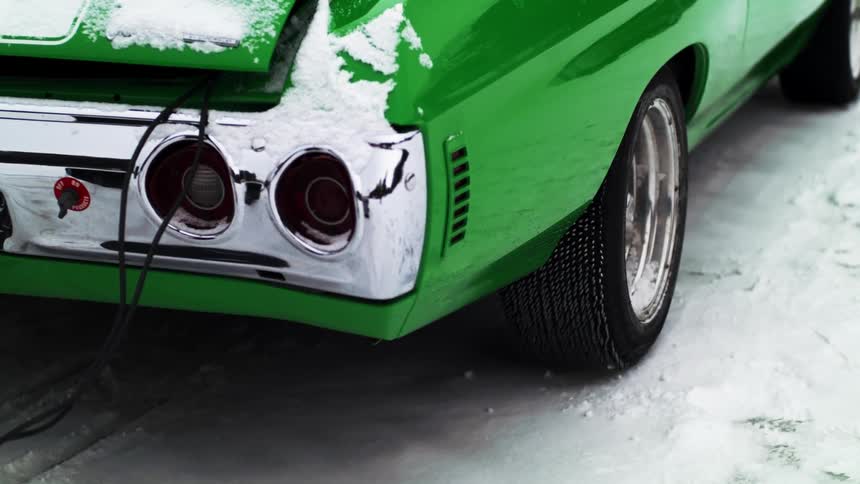 A green car is parked in the snow