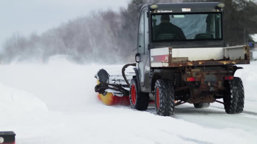 A man driving a snow plow removing snow outside