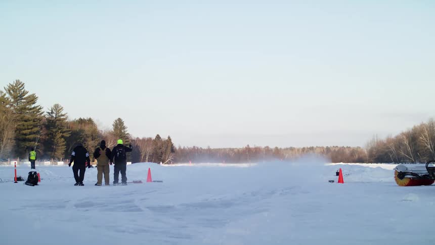 A group of people watch as cars race in the snow