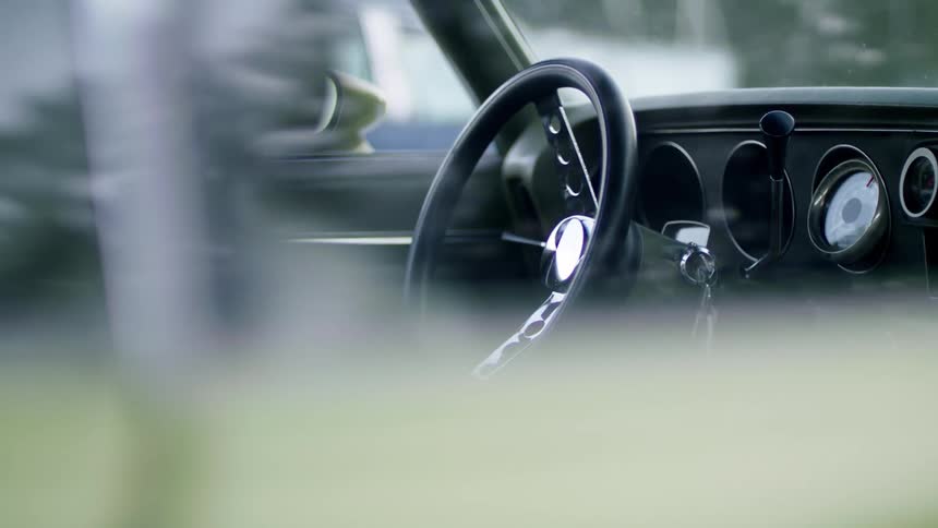 The steering wheel and dashboard of a car seen through the passenger side window
