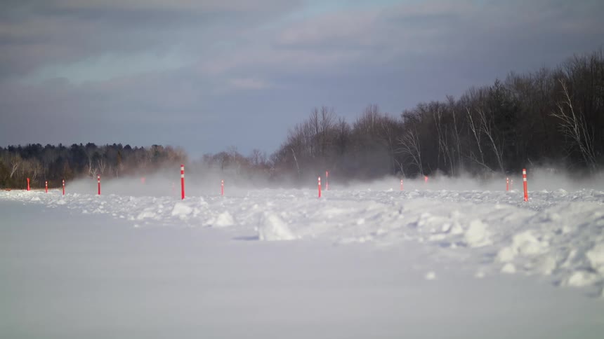 A pair of cars drag race across a field of snow on a winter day