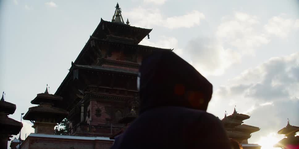 Pedestrians walking in front of an pagoda or temple at sunset