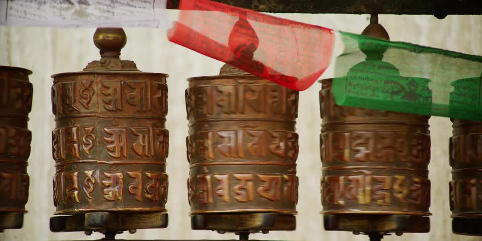 Two women touch and spin metal carvings as they walk past