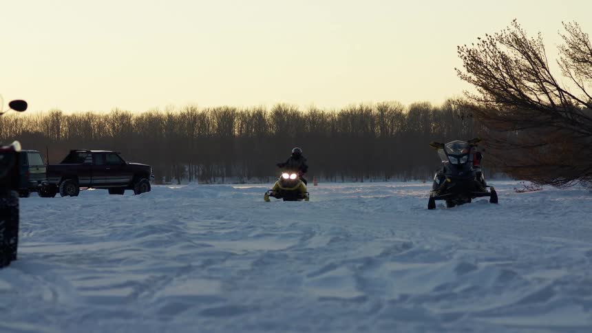 Two people driving on a snow mobile in a field