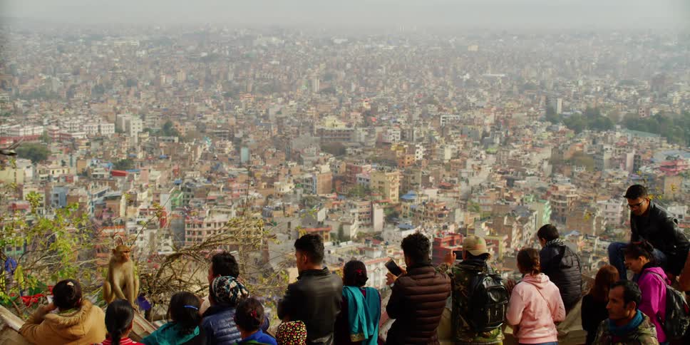 A crowd of people observing and taking photos of a large cityscape