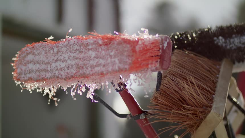Close up of brooms and mops outside with ice and snow on them