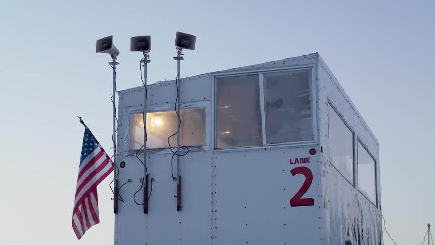 A flag hangs from a small building with people in it