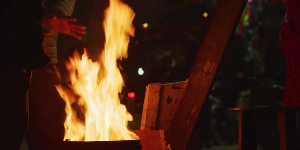 People gathered around a fire on the street of a city at night