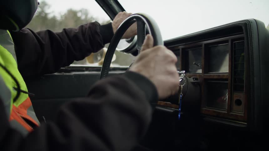 A person turns the ignition on in their vehicle and slowly starts driving