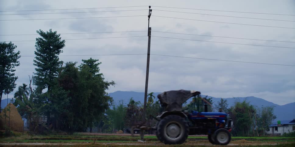 A blue tractor drives down a rural road