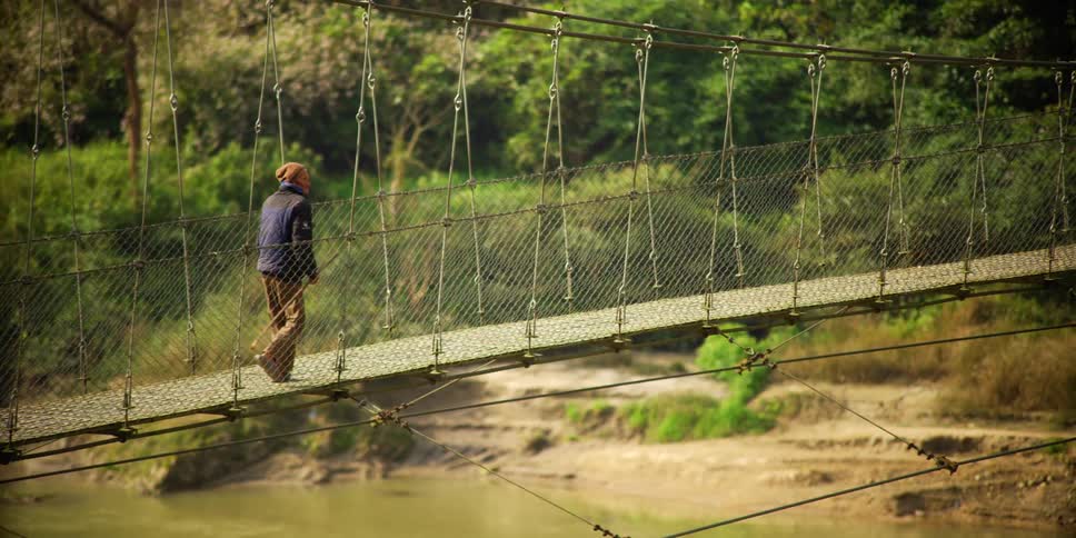 A person is hiking across a bridge in the wilderness