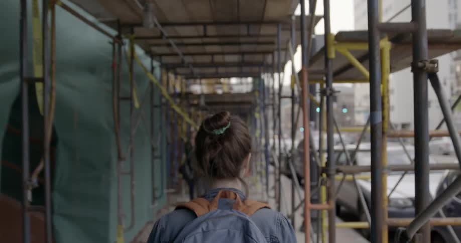 People are walking under a scaffolding on the sidewalk