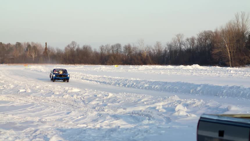 Two cars driving down a snow covered road