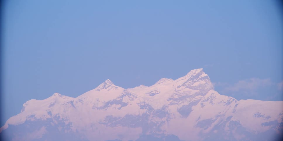 Snow covered peaks on a mountain range under a blue sky