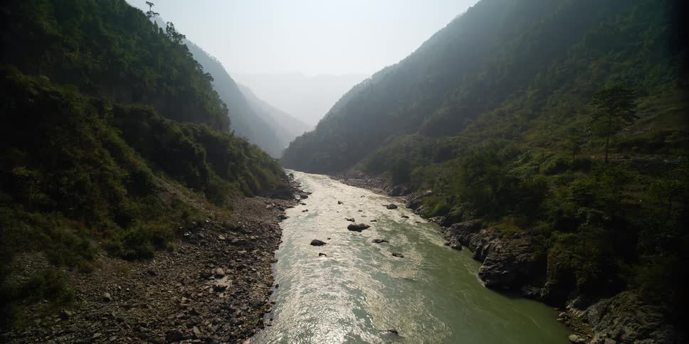 A narrow river at the bottom of a ravine beneath thick fog