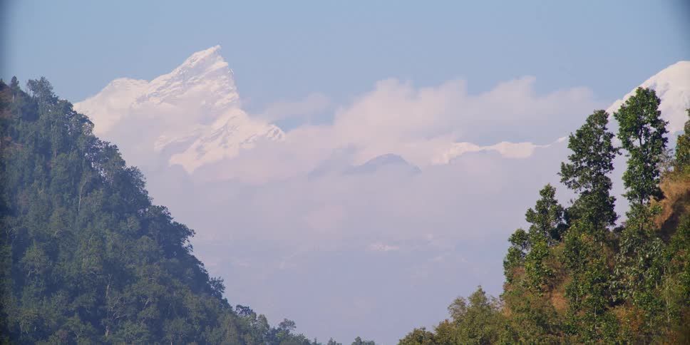 Snow covered peaks of a mountain range under the clouds in the horizon