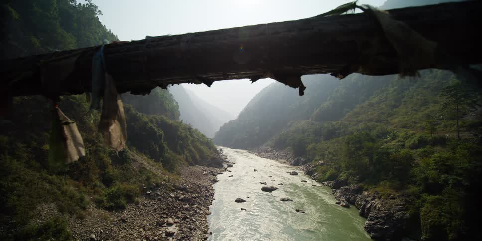 A river flows between two vegetation covered mountain slopes