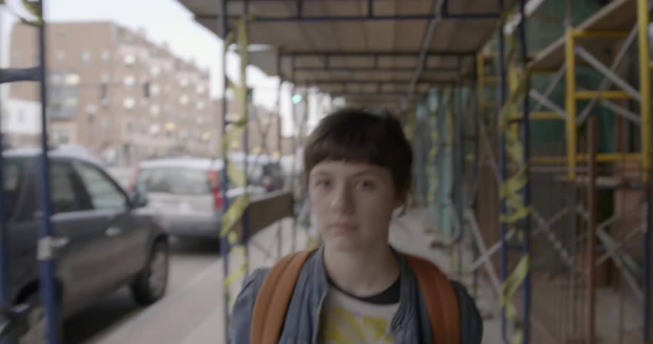 A woman is walking under scaffolding by a city building