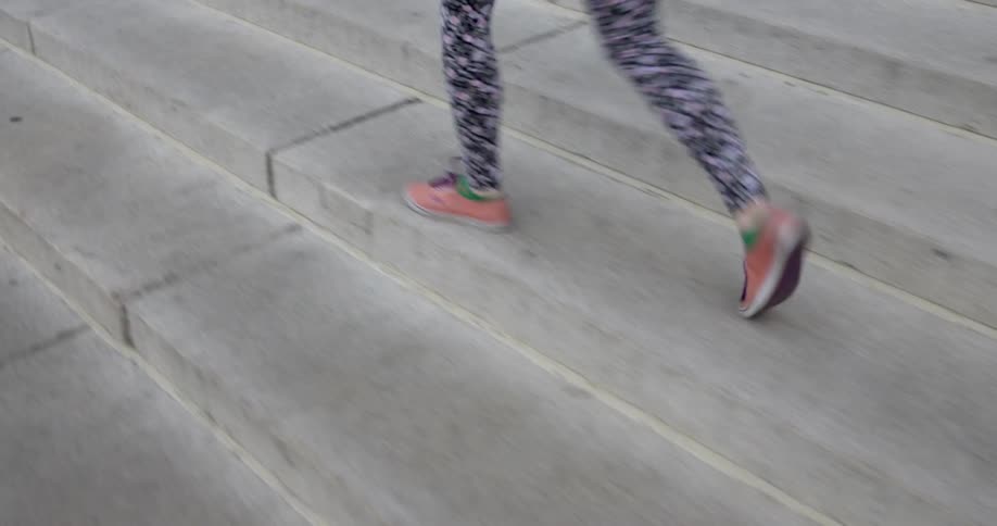 A person in black and white pants walks on steps