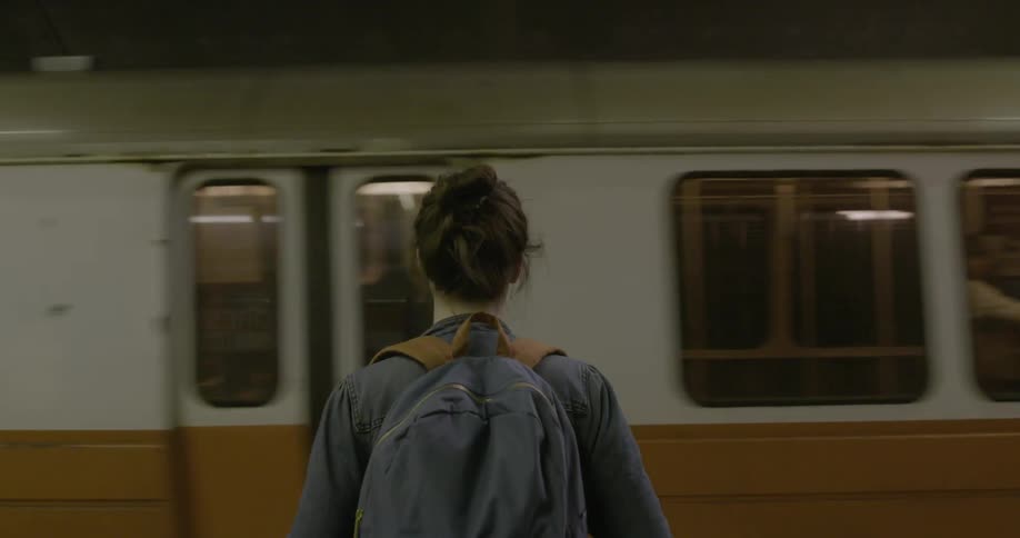 A woman is standing as a train moves in front of her