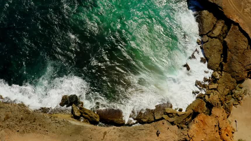 An aerial view of ocean water is displayed near an island