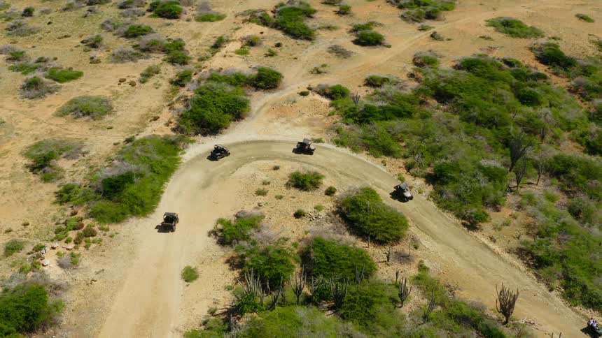 Cars are driving on a dirt road in a rural area
