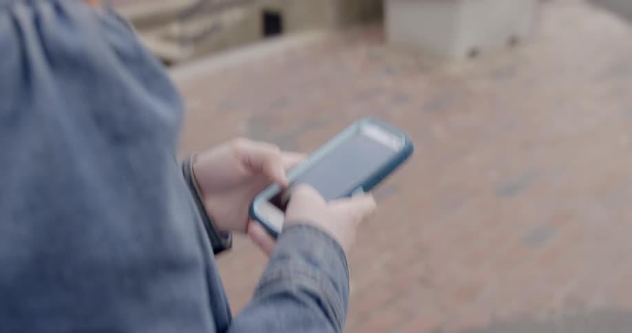 A woman is outside using her phone as people walk around ahead
