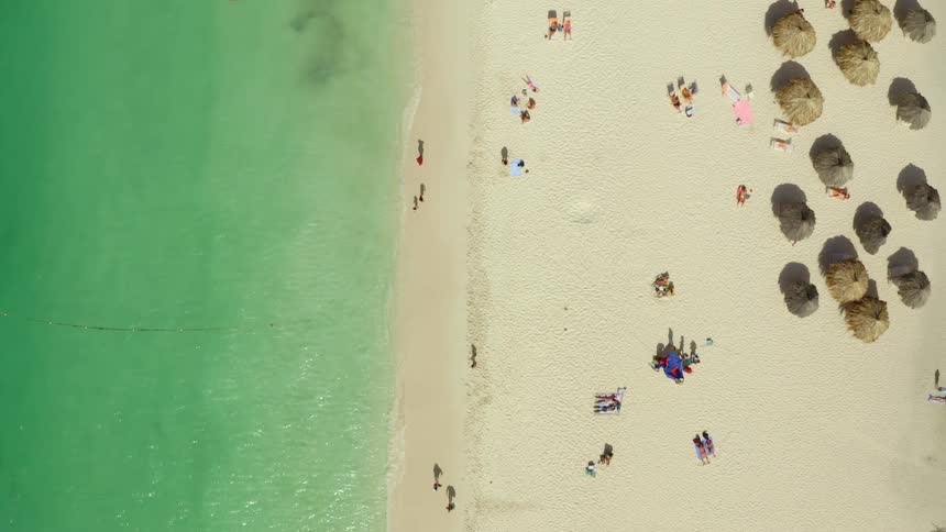 Aerial view of people walking along the shore and lying on a beach