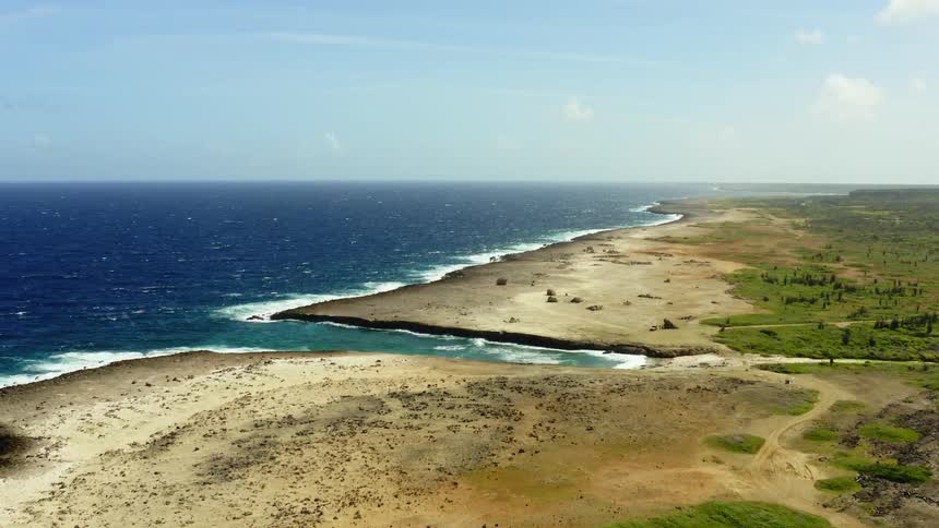 Aerial view of a narrow beach on the eroded coastline next to the ocean