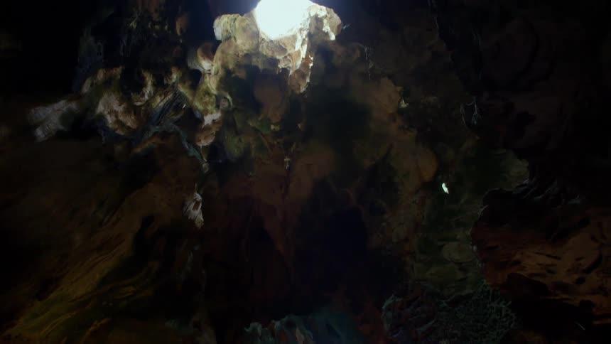 Colorful interior of a cave with sunlight entering through an opening in the ceiling