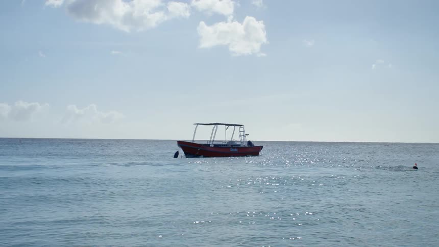 A person swimming away from a boat in the ocean