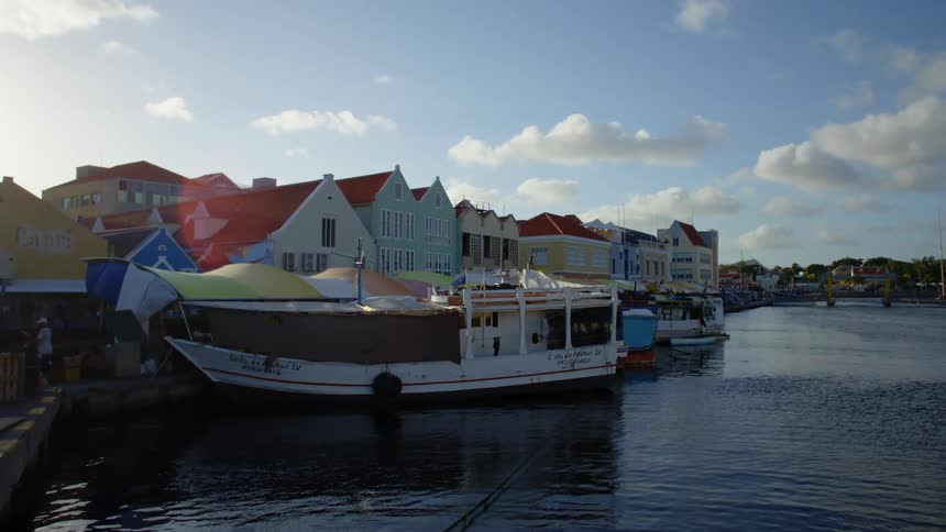 Boats parked at a dock with houses along the shore