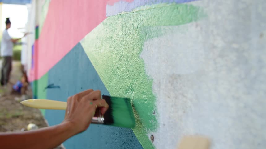 Two women painting the outside of a building