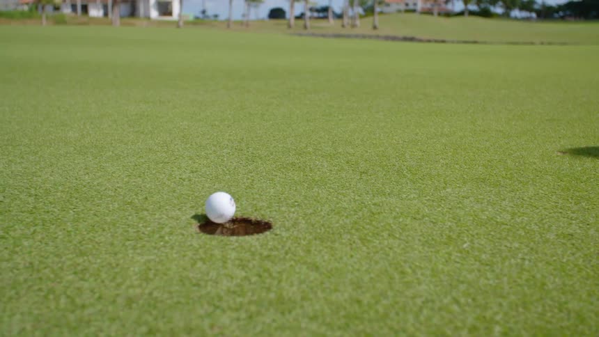 A golf ball going in to a hole